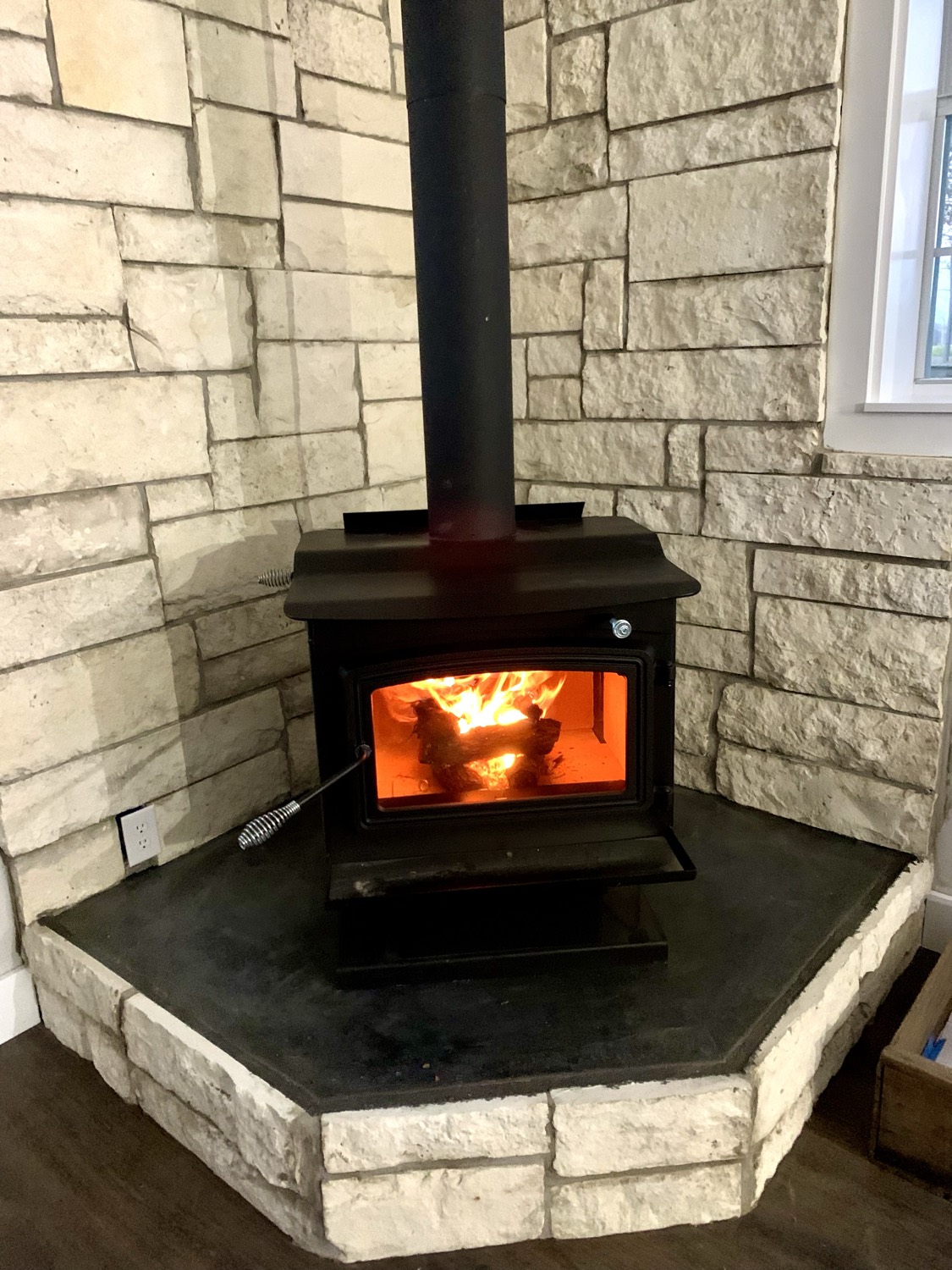 Wood stove set into a stacked-stone corner surround, laid stone by stone