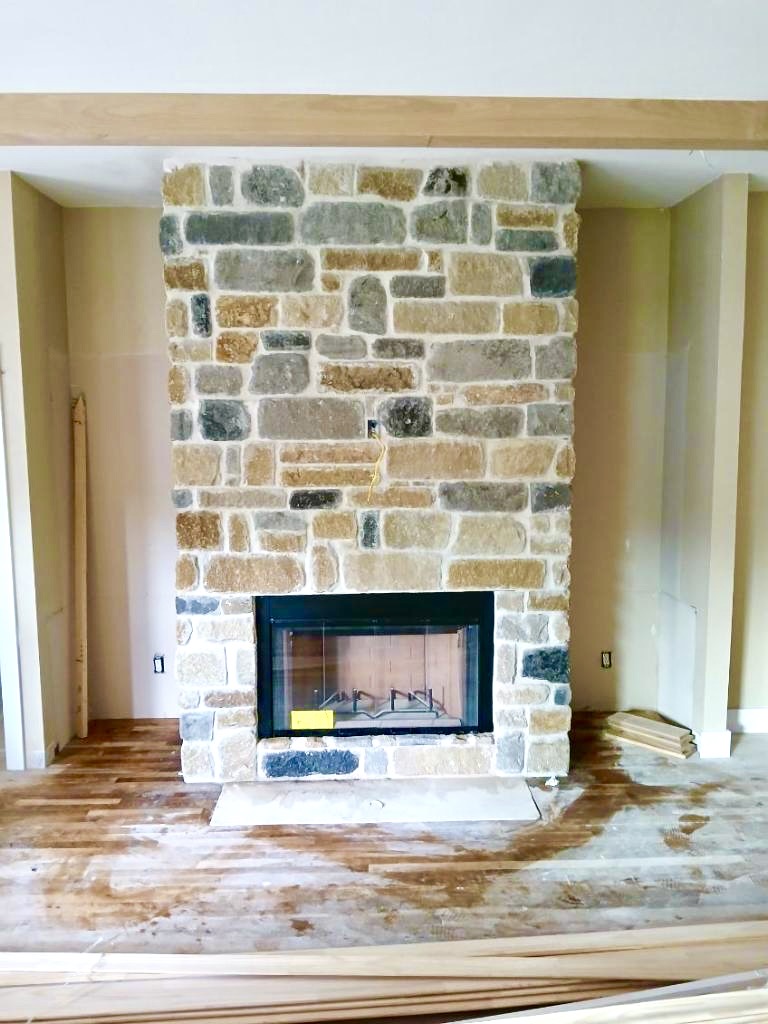 Light multi-tone stone fireplace with a glass firebox